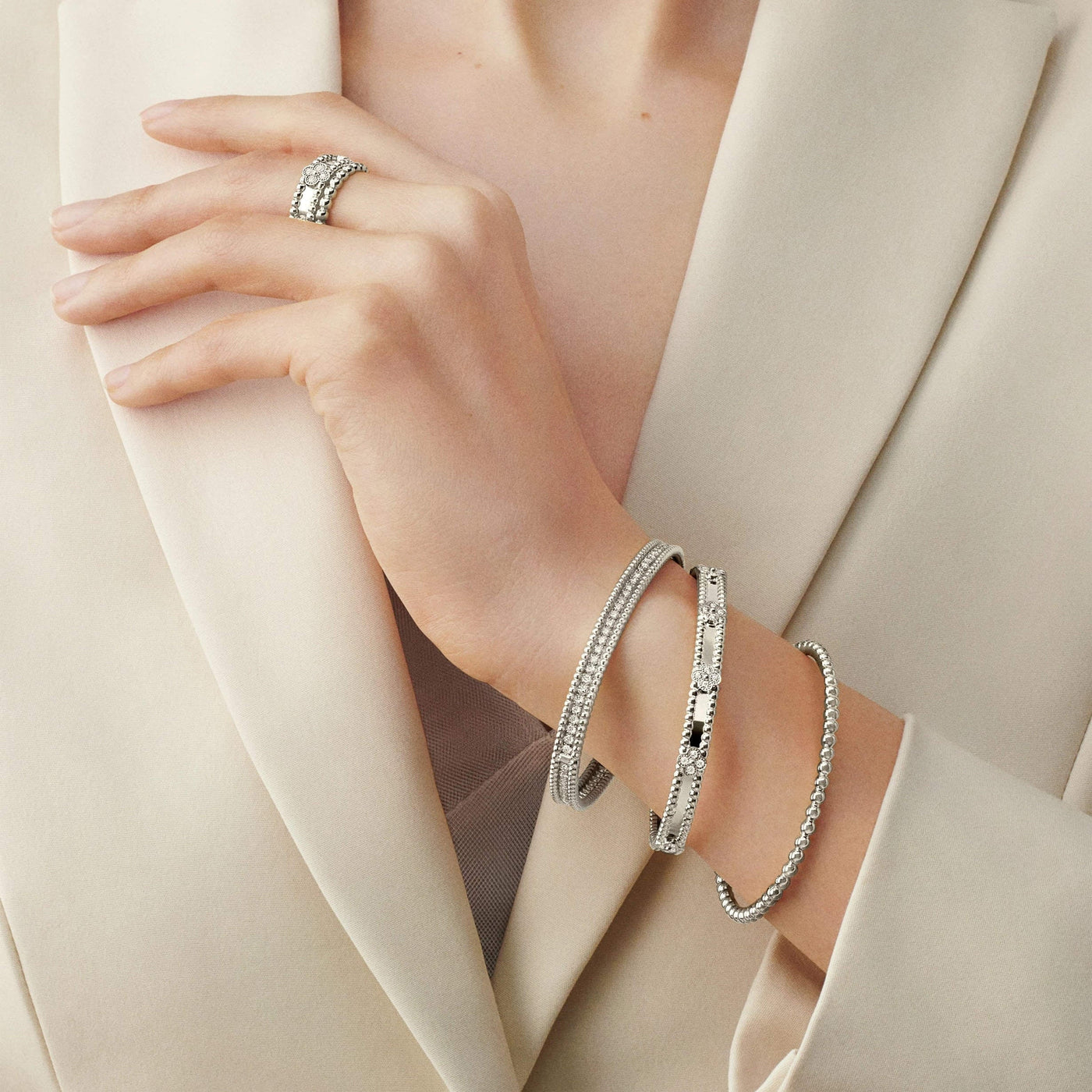 Model wearing silver Fleuron Paris Perlee Bangle - 18k gold plated with zircon, styled with matching ring and bracelets for a luxe look.